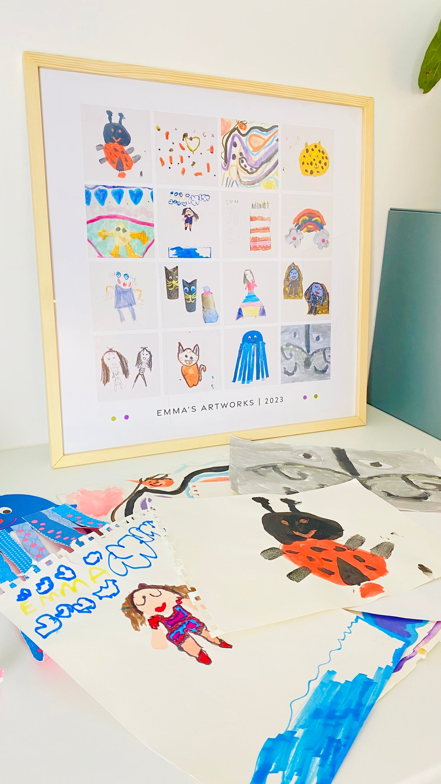 Framed children's artwork with various illustrations on a white surface.